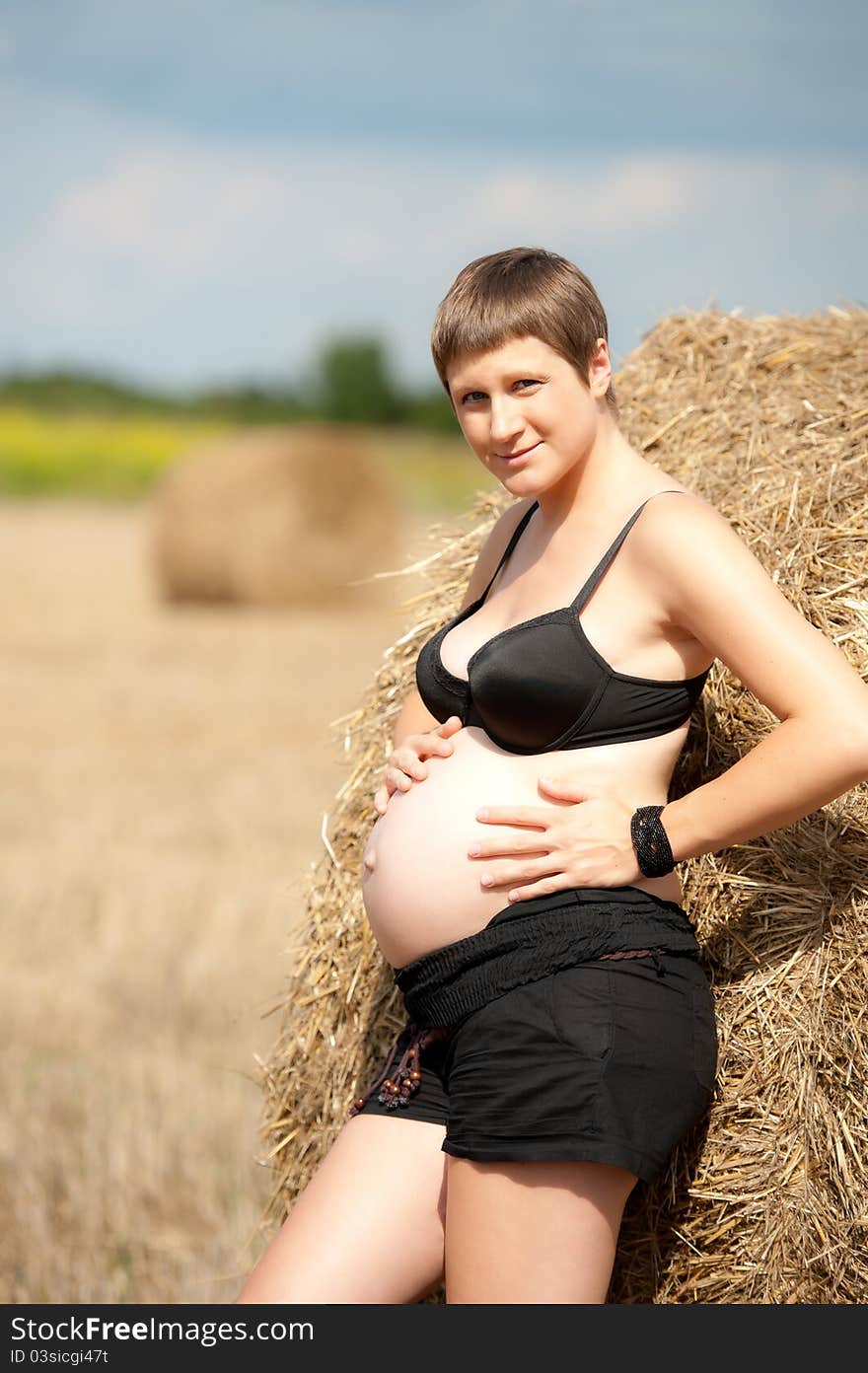 Pregnant Woman On The Field With Straw