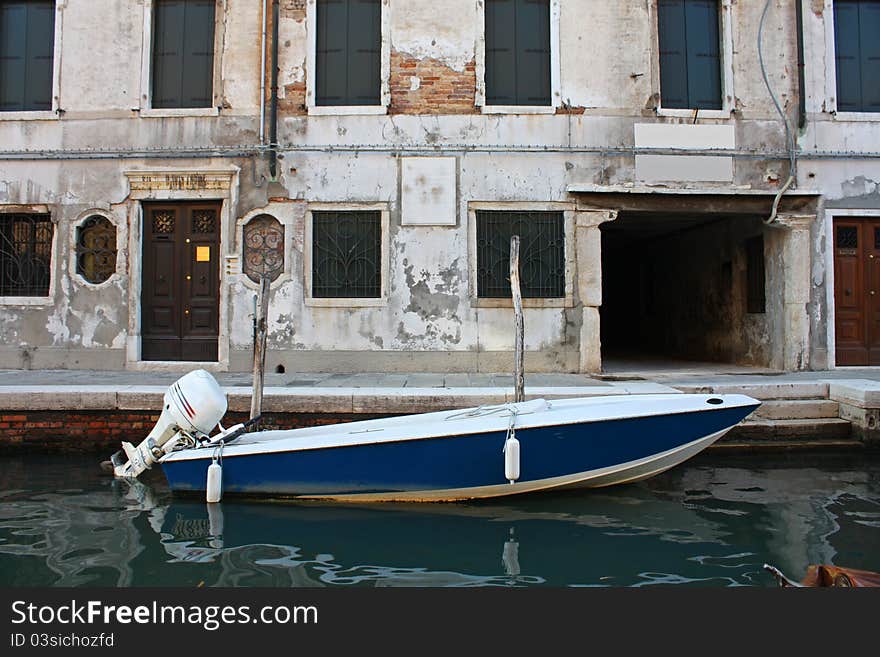 Blue boat parked in a canal of Venice, Italy