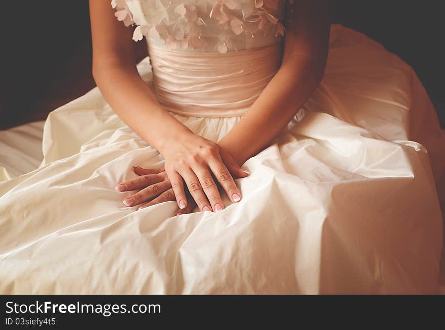 Woman in a wedding dress holding hands on the knees. Woman in a wedding dress holding hands on the knees