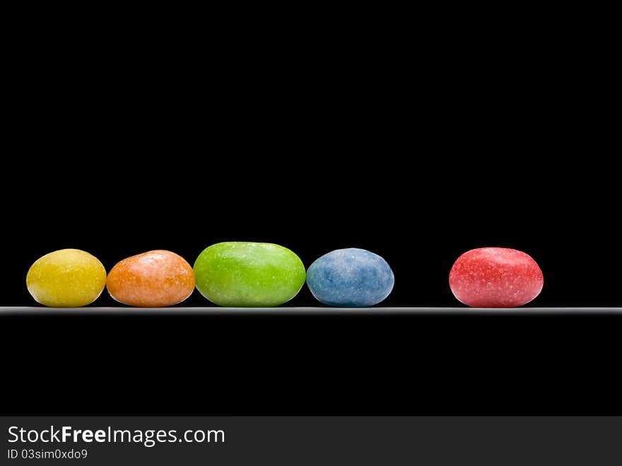 Multi-coloured sweets (five pieces) on a black background. Multi-coloured sweets (five pieces) on a black background.