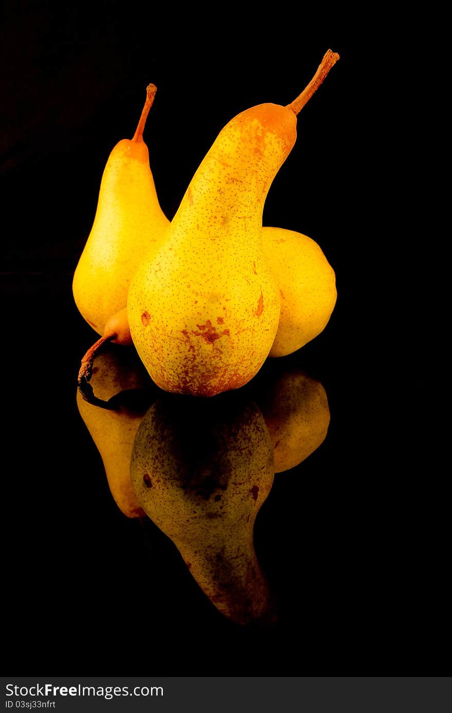 Three pears. Black background. Reflections in a black mirror