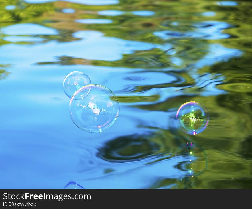 Soap bubbles flying above blue water. Soap bubbles flying above blue water.