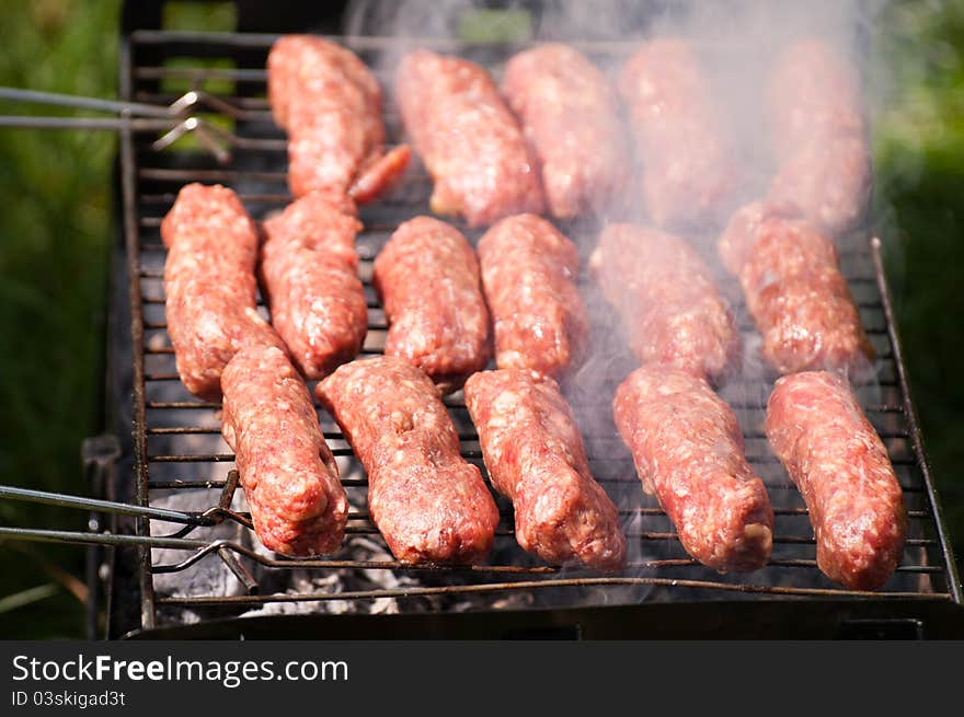 Traditional Romanian barbecue raw meat (mici, mititei) on hot grill. Traditional Romanian barbecue raw meat (mici, mititei) on hot grill.