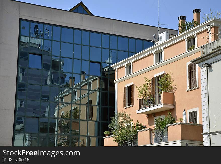 Flowers on balcony on a red building near a glass building. Flowers on balcony on a red building near a glass building