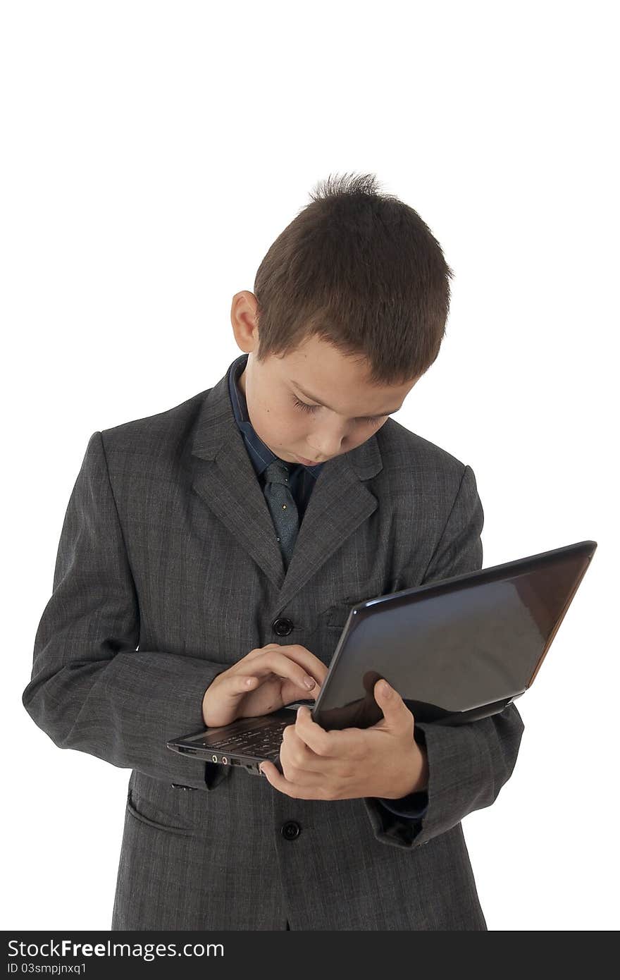 The young eleven-year boy works on the laptop having control over it. The young eleven-year boy works on the laptop having control over it