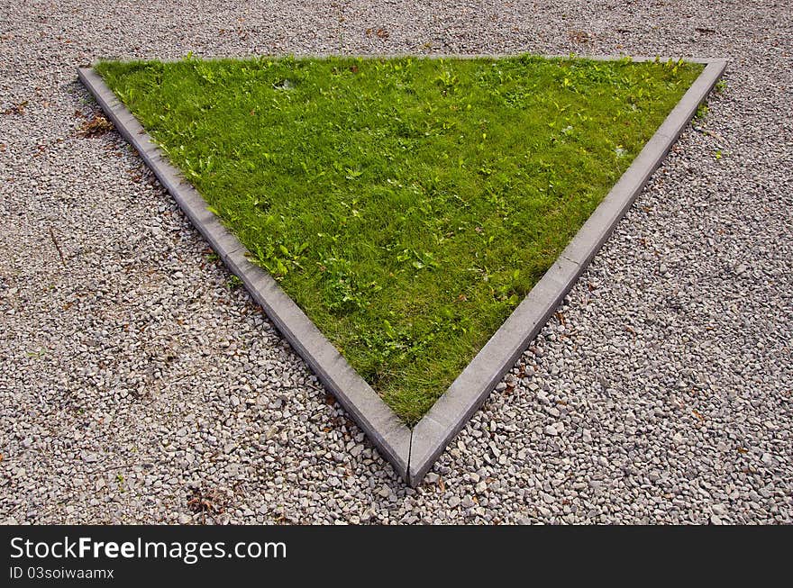 Green triangular island of grass surrounded by path in park. Green triangular island of grass surrounded by path in park.