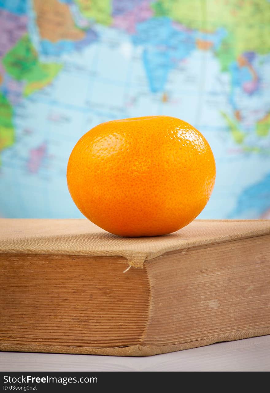 Orange on old book on globe background. Orange on old book on globe background