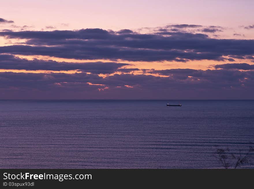 Picture of the sea horizon with light waves on the surface with the items on the roads of the ship against the background of the sky-lit rising sun. Picture of the sea horizon with light waves on the surface with the items on the roads of the ship against the background of the sky-lit rising sun.