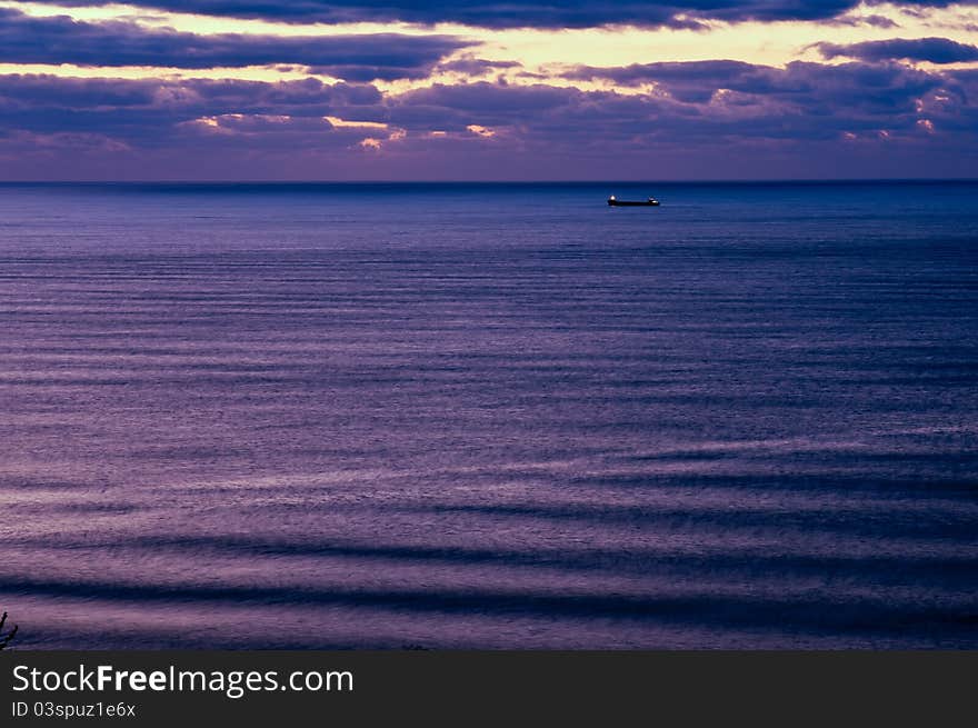 Picture of the sea horizon with light waves on the surface with the items on the roads of the ship against the background of the sky-lit rising sun. Picture of the sea horizon with light waves on the surface with the items on the roads of the ship against the background of the sky-lit rising sun.