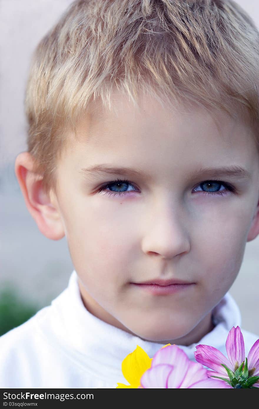 Portrait of the boy with a bouquet of flowers in hands.