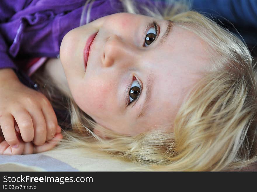 Beautiful little girl lying on bed at house