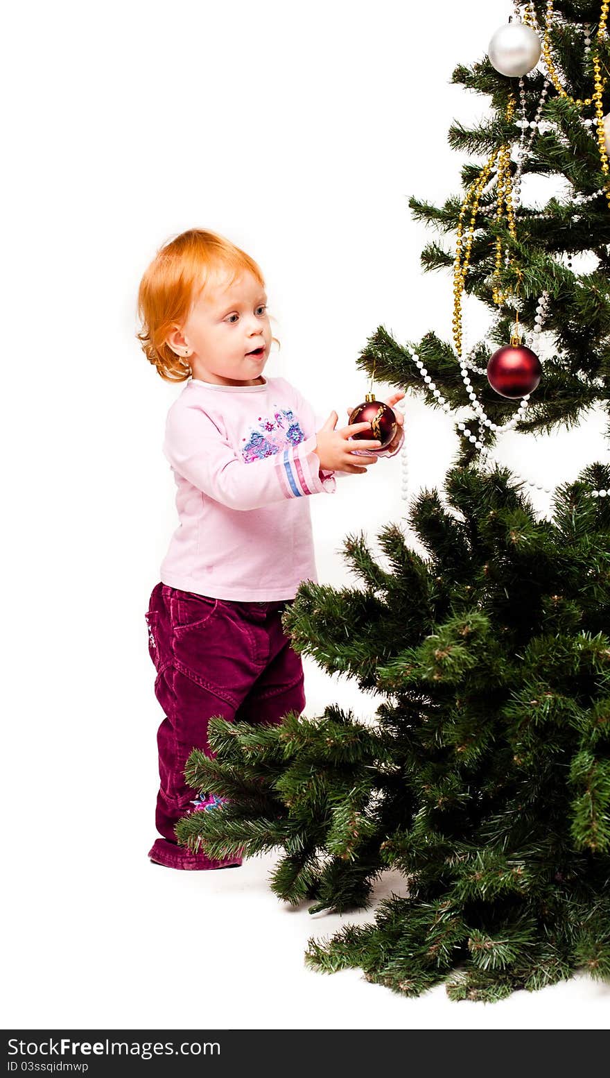 A little girl decorates a new-year tree on a white background