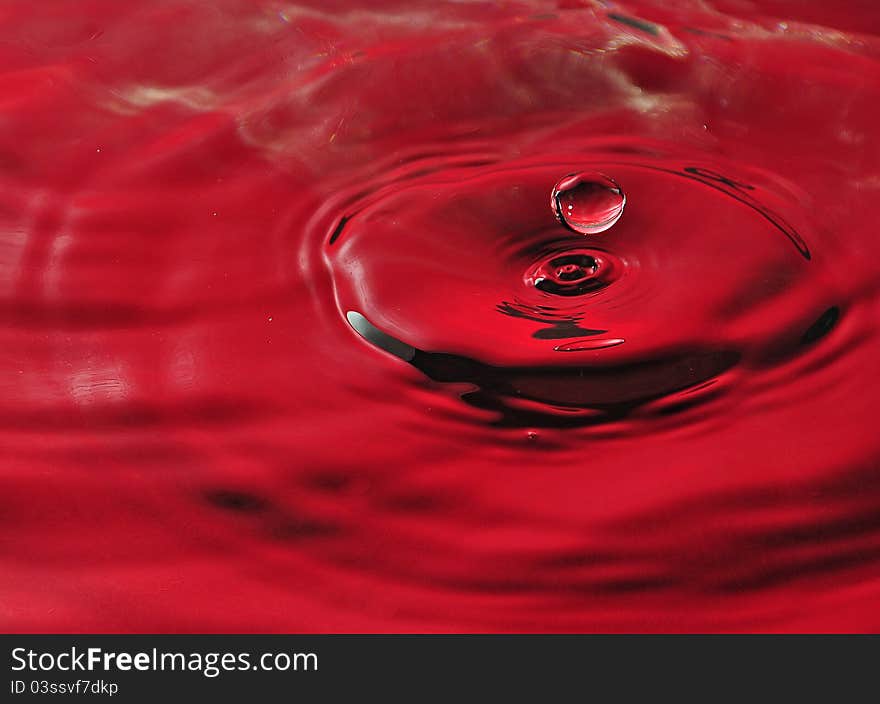 A water splash with drops in red color. A water splash with drops in red color.