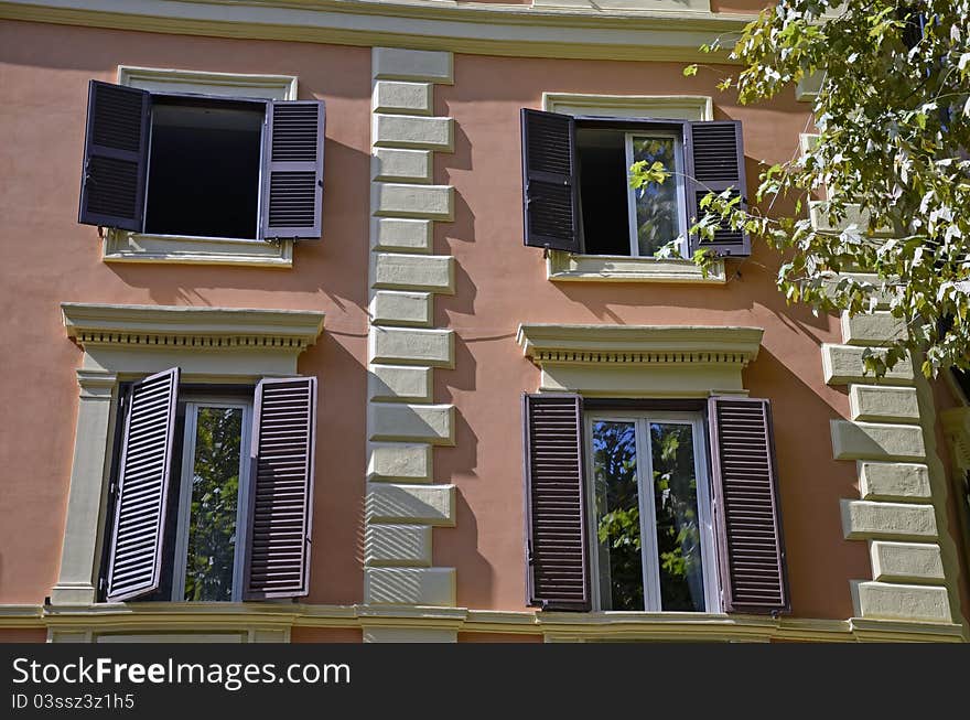 Four windows and vegetation in front of a modern building