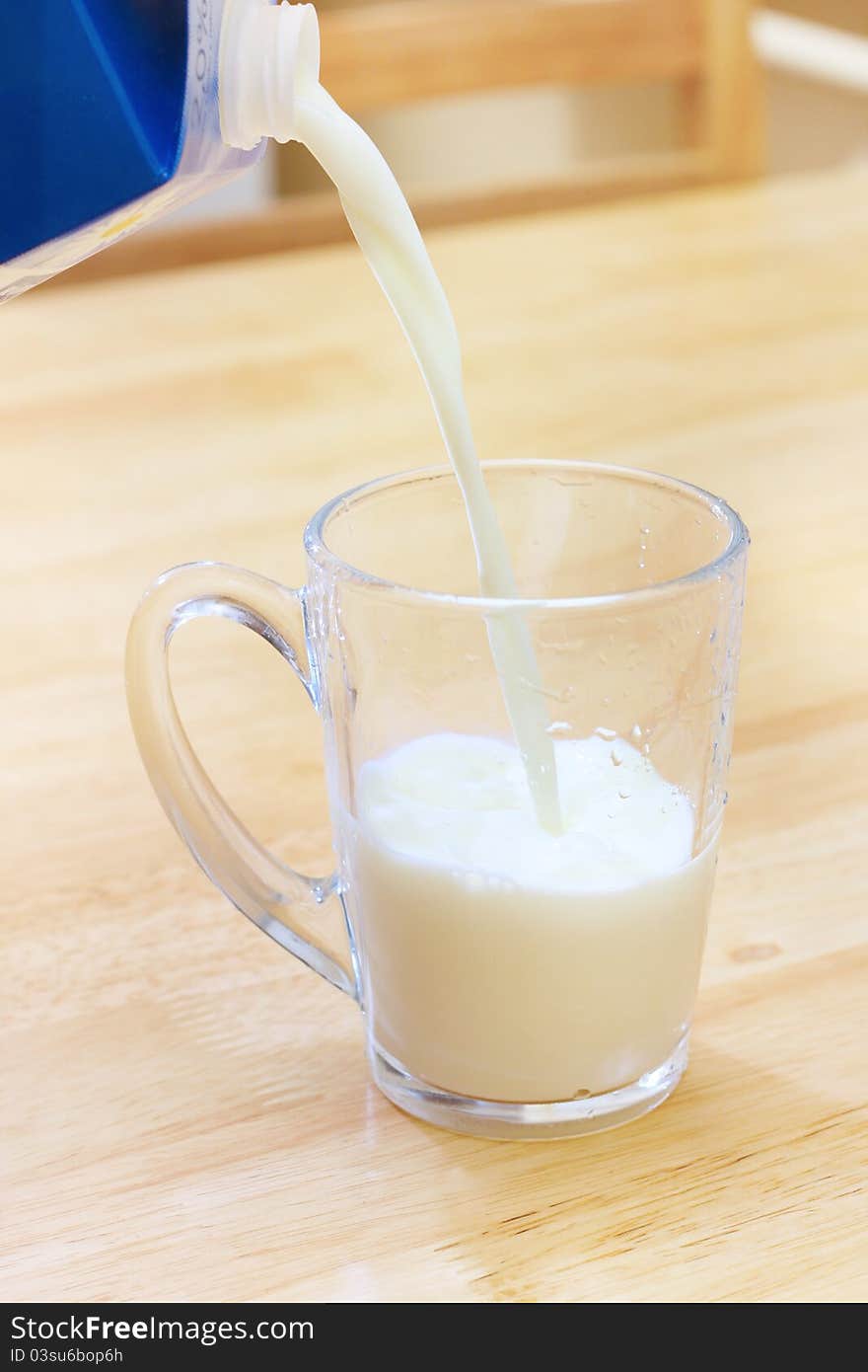 Pouring milk into a glass on wooden table