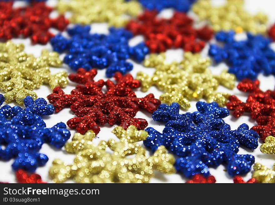 Red, blue and yellow plastic snowflakes on white. Red, blue and yellow plastic snowflakes on white