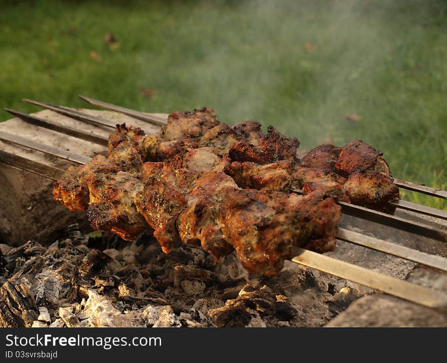 Smoke and barbecue of meat on skewers over a hot charcoal. Smoke and barbecue of meat on skewers over a hot charcoal