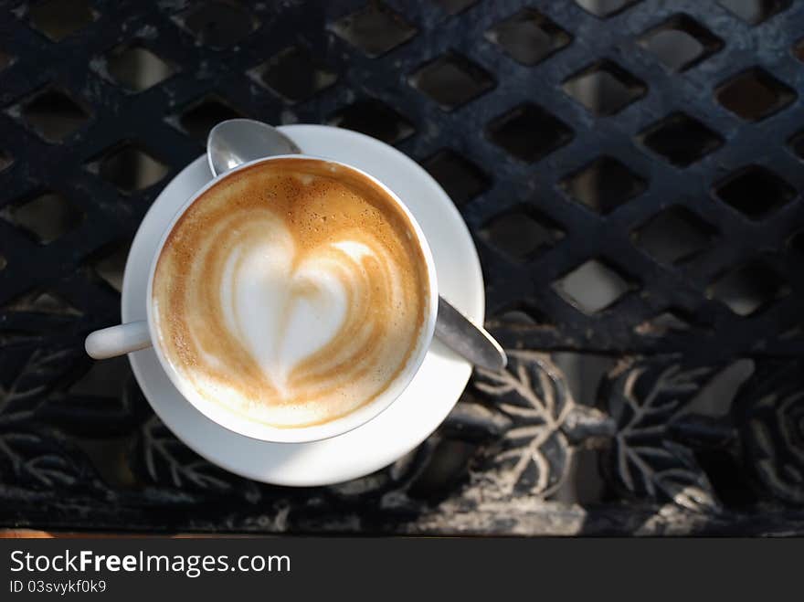 Alfresco cup of coffee, the froth has swirled into a heart shape. Alfresco cup of coffee, the froth has swirled into a heart shape.