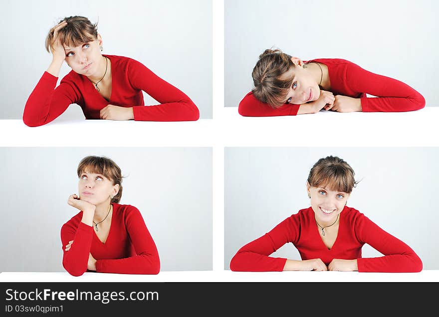 A pensive young woman in a red sweater at the desk, isolated on white