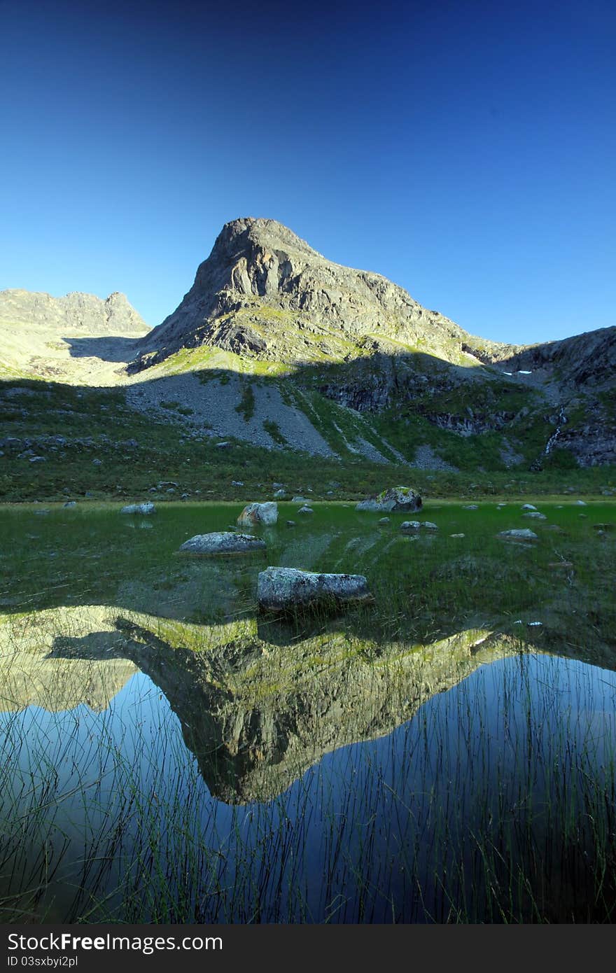 Tall mountain peak reflected in a natural lake, Troms County, northern Norway. Tall mountain peak reflected in a natural lake, Troms County, northern Norway