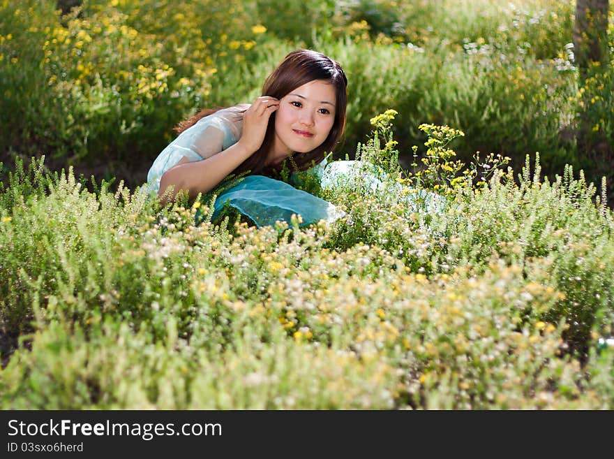 Young Beautiful Girl Laying On The Flowers Field