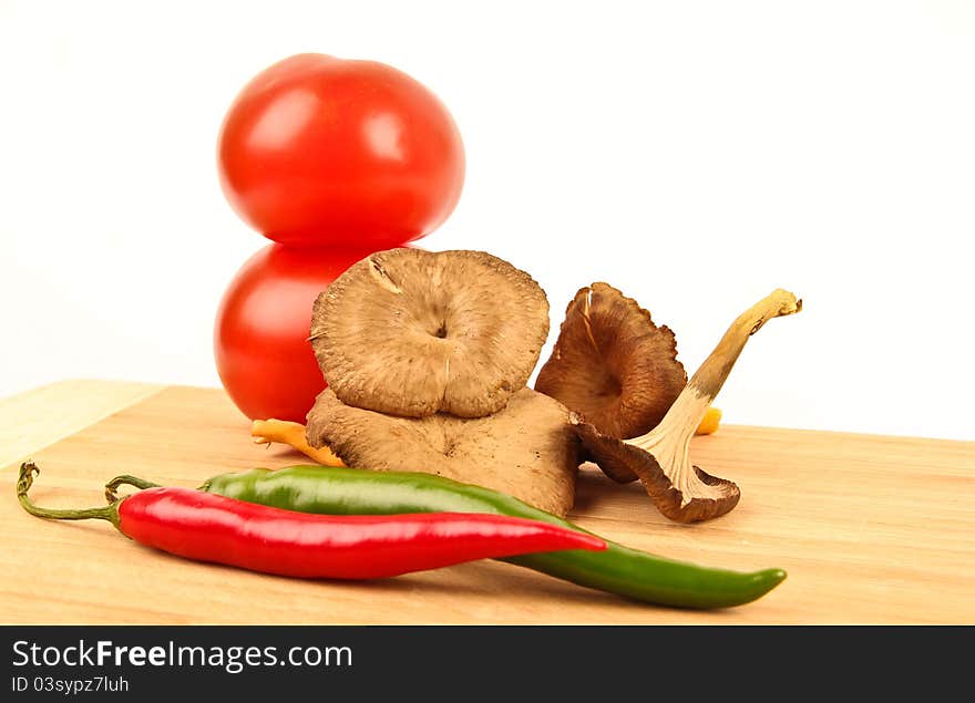 Fresh funnel chanterelle, with tomatoes in the background, and fresh chili in front