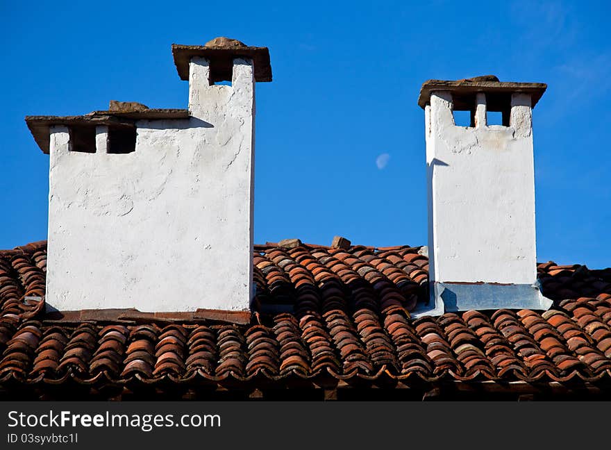 Tiled house roof with two stone chimneys. Tiled house roof with two stone chimneys