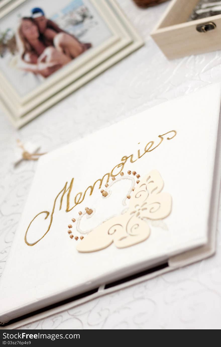 White photo album with Memories written with golden font and blurred picture of couple in the background