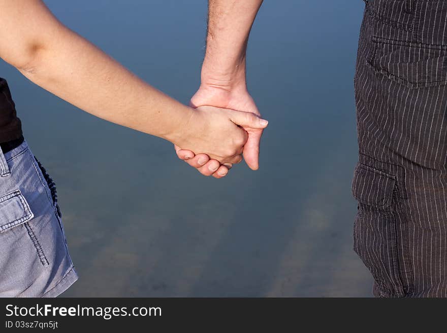 Close-ups of couple hands over blue lake