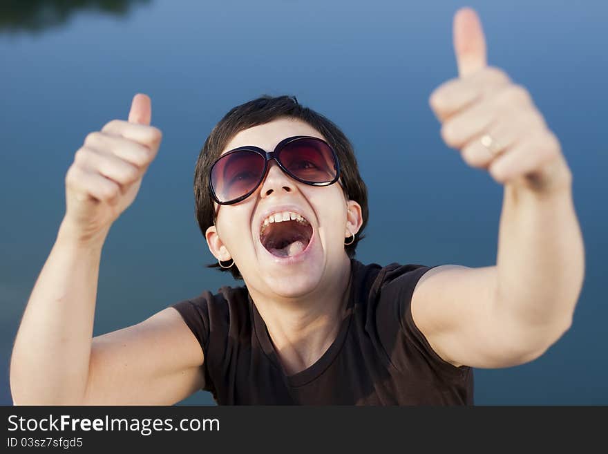 Young brunette girl with big funny sunglasses making thumbs up gesture - shallow depth of field. Young brunette girl with big funny sunglasses making thumbs up gesture - shallow depth of field