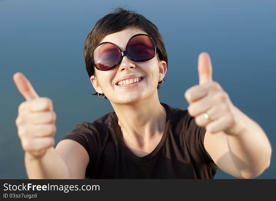 Young brunette girl with big funny sunglasses making thumbs up gesture - shallow depth of field. Young brunette girl with big funny sunglasses making thumbs up gesture - shallow depth of field