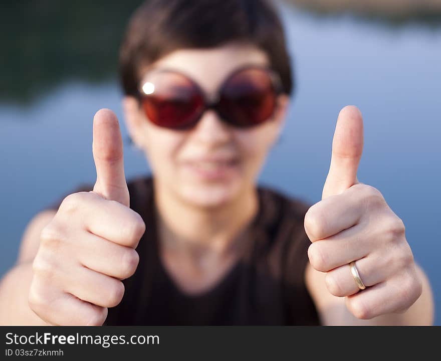 Young brunette girl with big funny sunglasses making thumbs up gesture - shallow depth of field. Young brunette girl with big funny sunglasses making thumbs up gesture - shallow depth of field