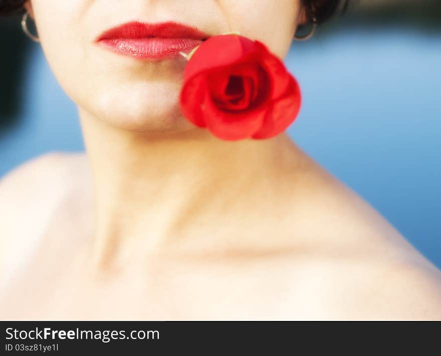 Woman with red lips holding red rose in mouth. Woman with red lips holding red rose in mouth