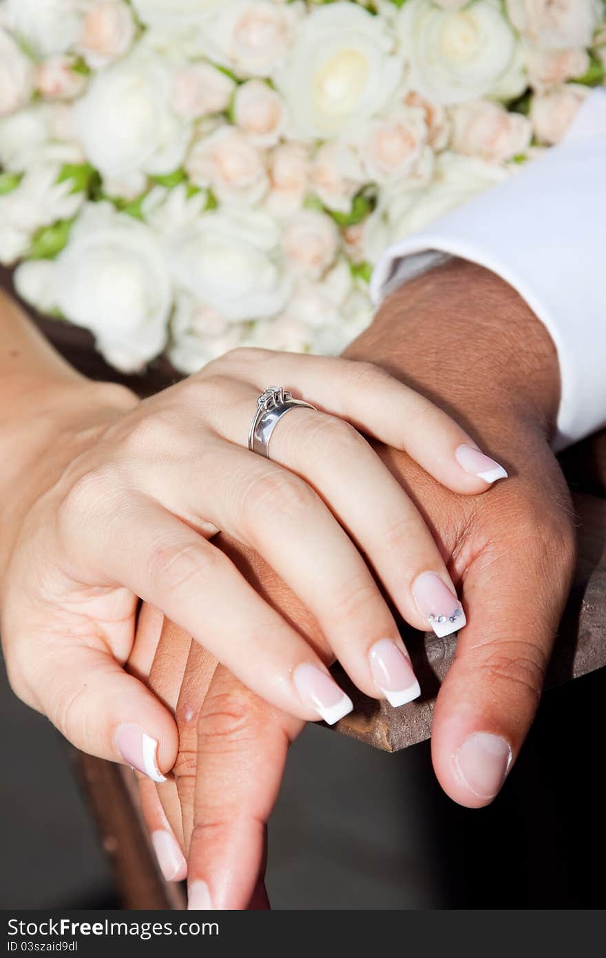 Hands and rings on wedding bouquet