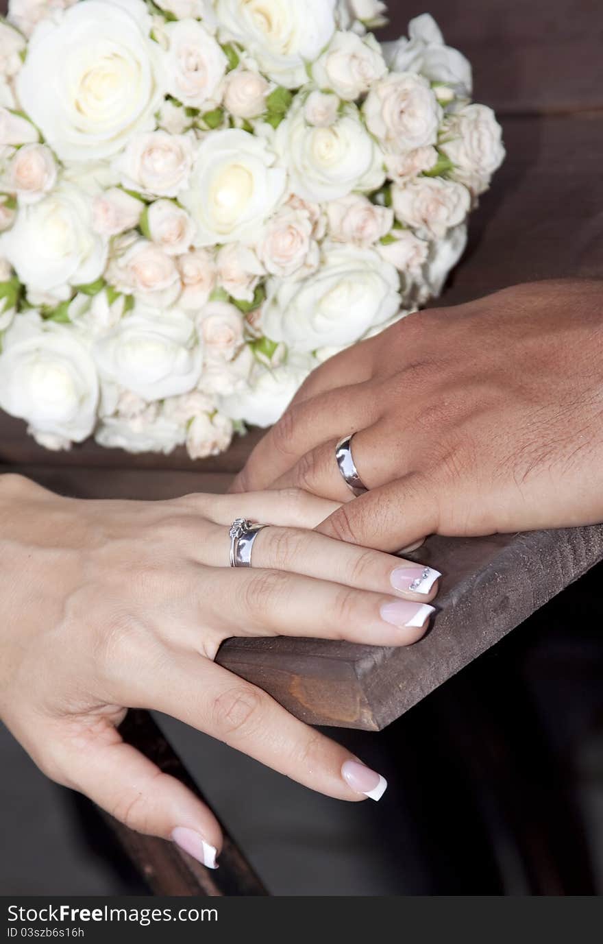 Hands and rings on wedding bouquet