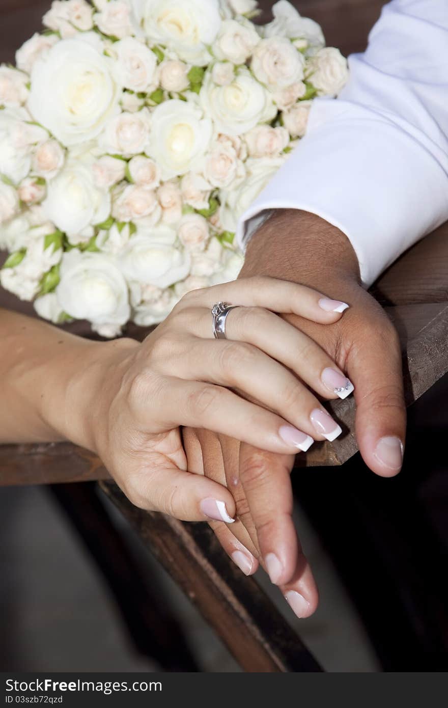 Hands and rings on wedding bouquet