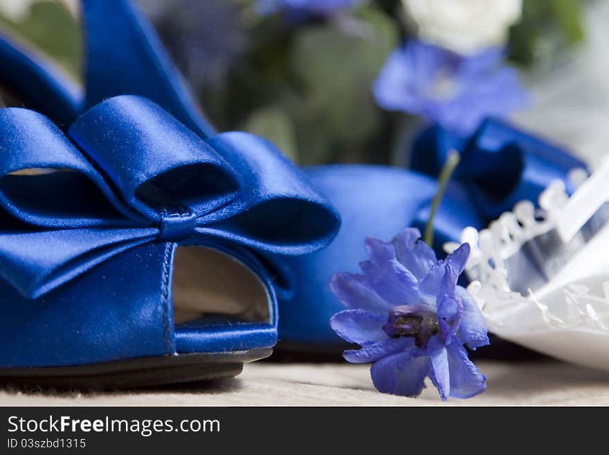 Blue wedding shoes and bouquet in the background