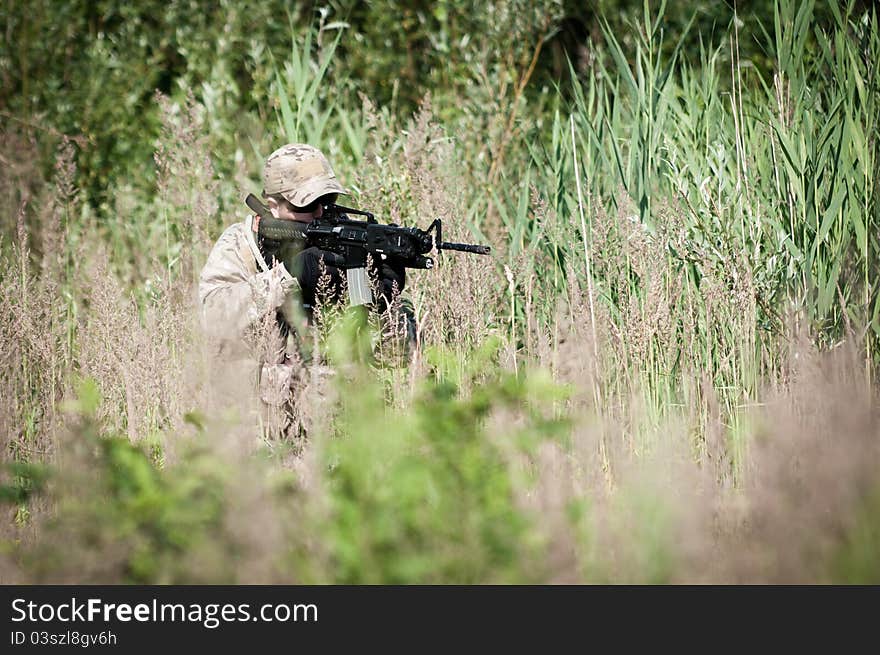 Special forces soldier on battle field, hiding in grass, on patrol. Special forces soldier on battle field, hiding in grass, on patrol