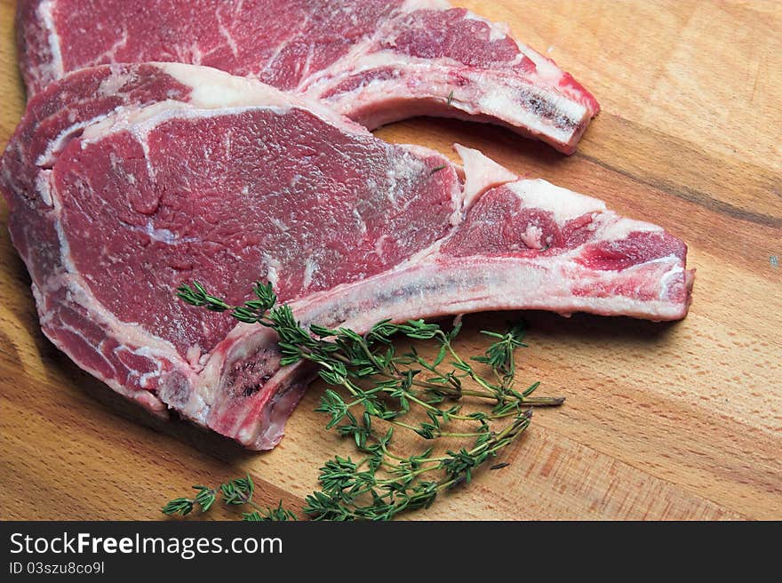 Two raw steaks with a sprig of thyme