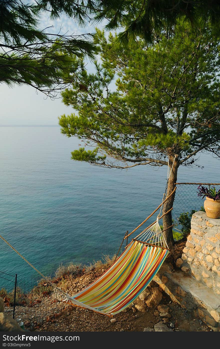 Rest and relaxation: hammok by the sea under a pine tree