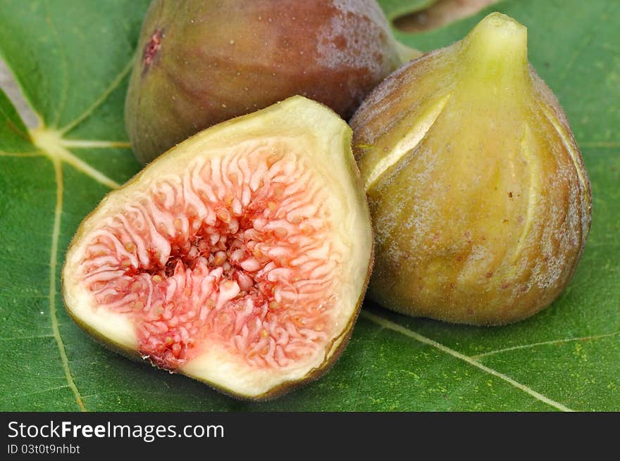 Half of figs and fig whole resting on a fig leaf