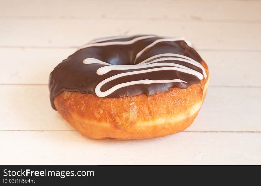 Donut covered in chocolate icing on grunge wooden background. Donut covered in chocolate icing on grunge wooden background