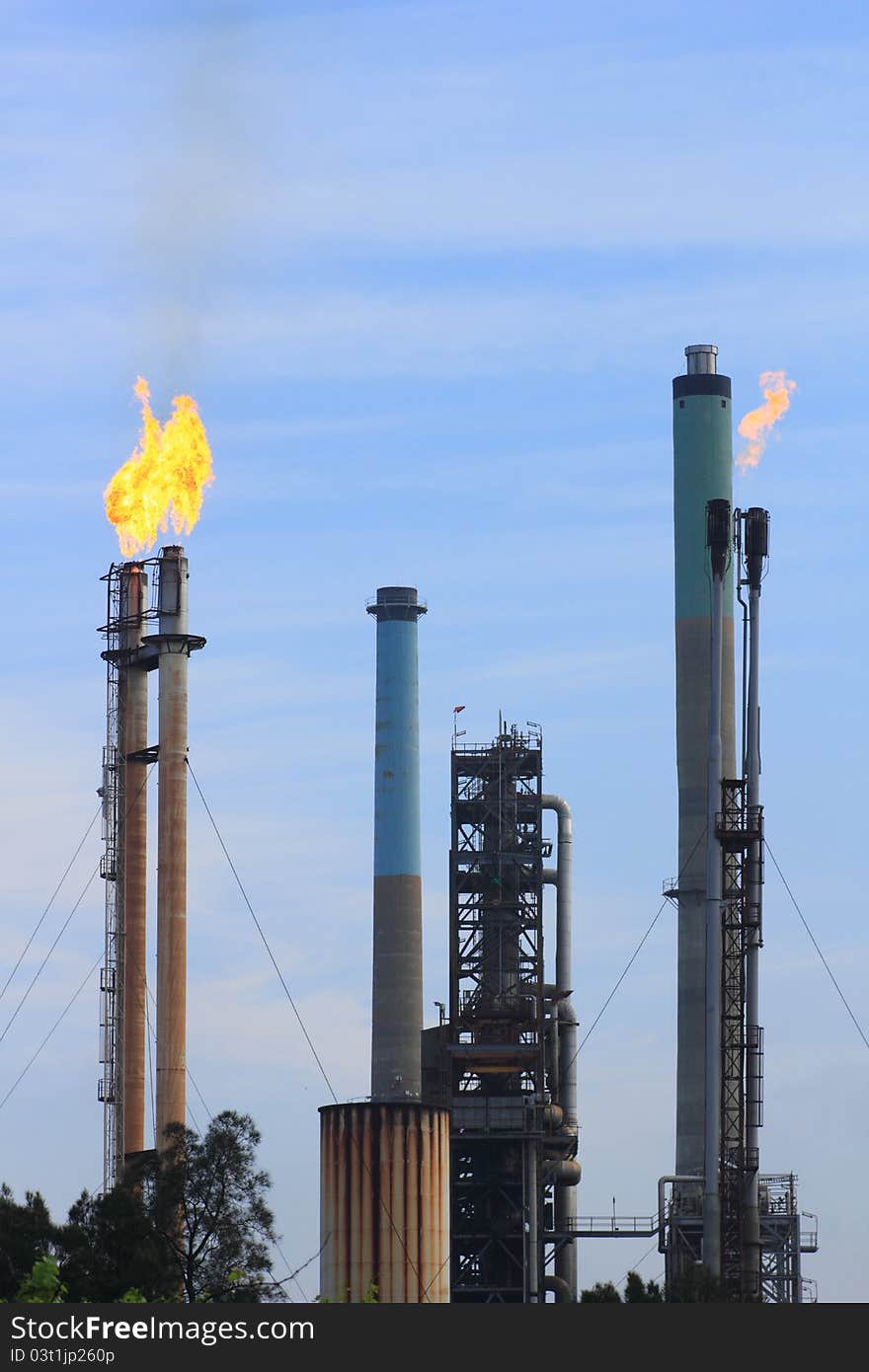 Flames coming out of free-standing chimneys of a refinery. Flames coming out of free-standing chimneys of a refinery