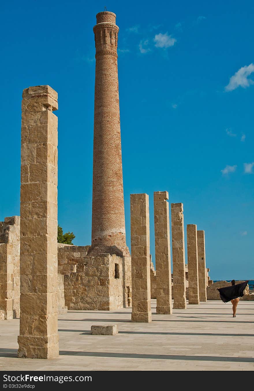 Walking woman on tuna fishing ruins natural oasis during sunset, there is an brick smokestack and pillars. Walking woman on tuna fishing ruins natural oasis during sunset, there is an brick smokestack and pillars.