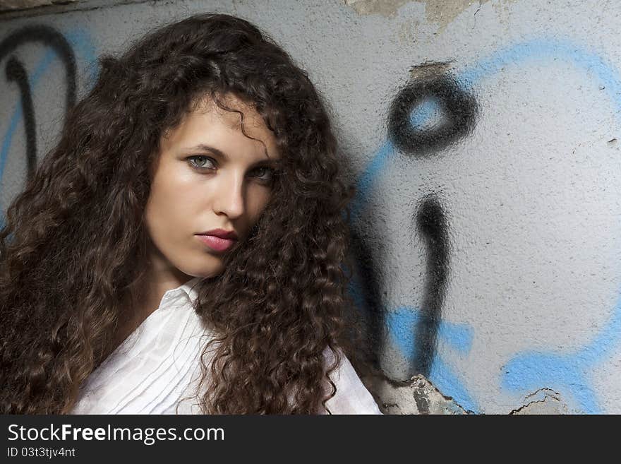 Woman with curly hair holding a protective cap in hand and looks into the camera