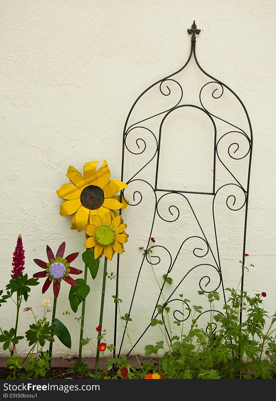 Metal Flowers And Trellis Against A White All.