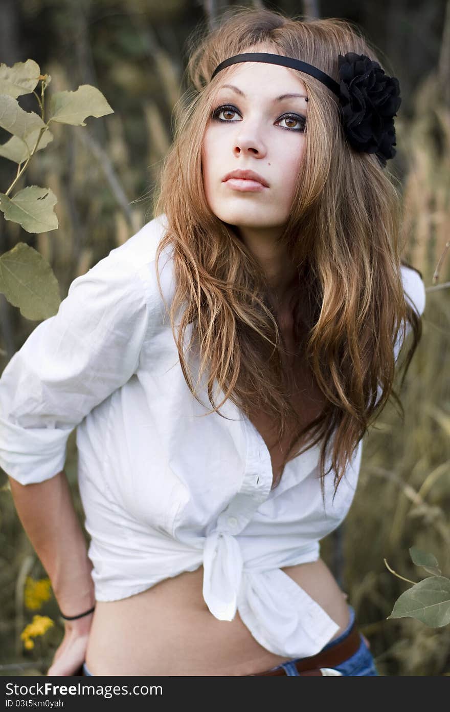 Young beautiful woman with brown eyes stands in a pale grass. Young beautiful woman with brown eyes stands in a pale grass.