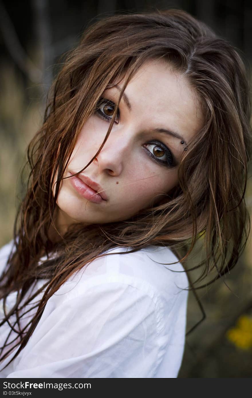 Young beautiful woman with brown eyes stands in a pale grass. Young beautiful woman with brown eyes stands in a pale grass.