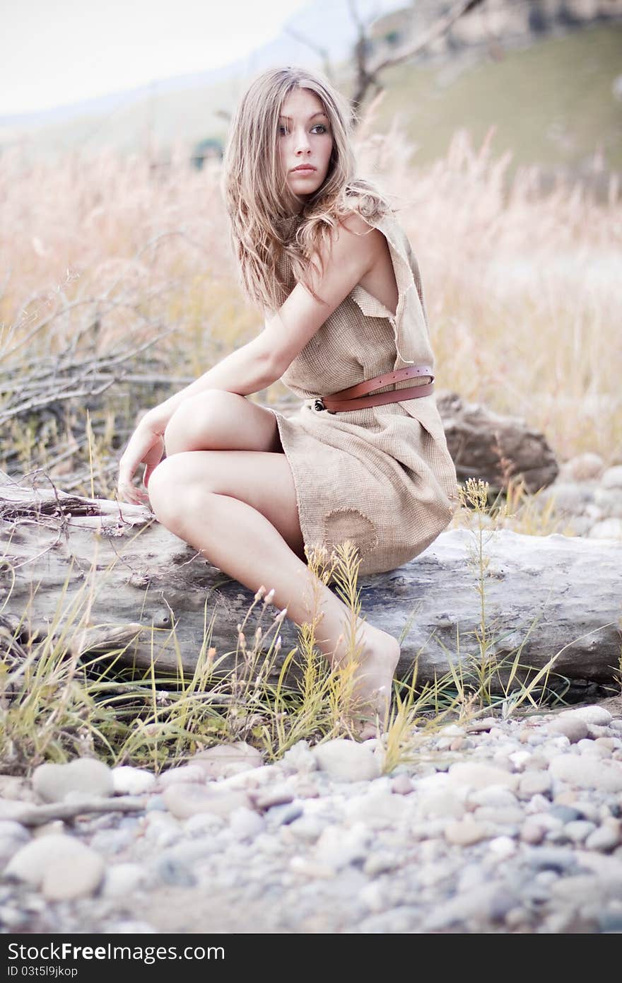 Beautiful young woman sitting on the peach-colored meadow. Beautiful young woman sitting on the peach-colored meadow.