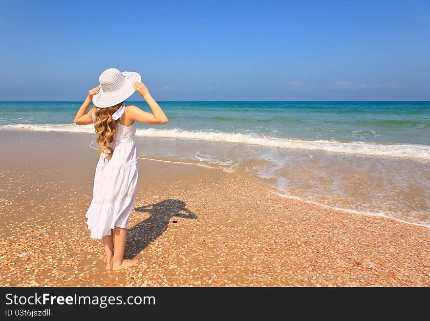 Girl in white dress and white hat standing on the beach. Girl in white dress and white hat standing on the beach